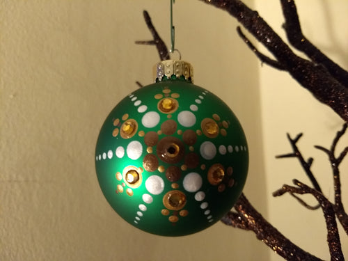 A painted starburst design in gold and white on a green ornament. Embellished with crystal.