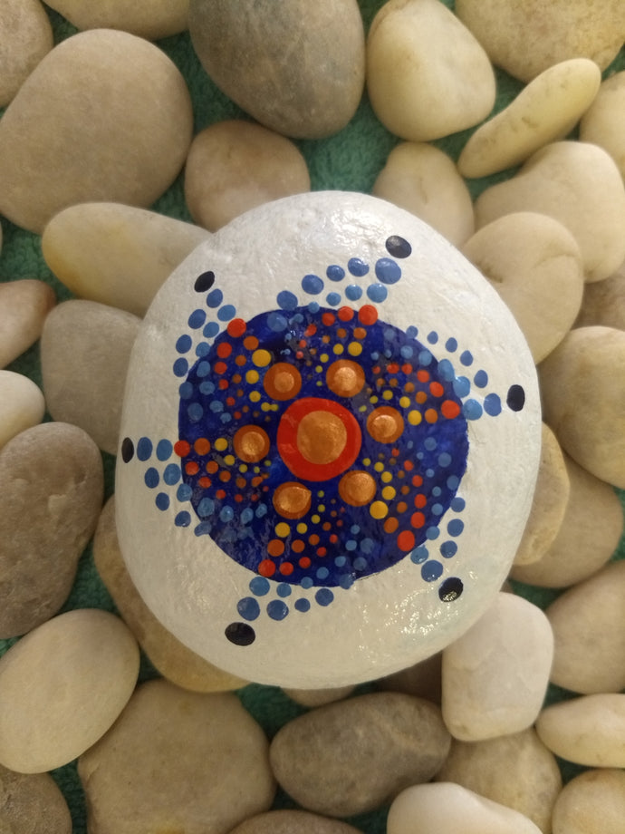 A small palm-sized meditation stone with a painted circular design in blue and orange.