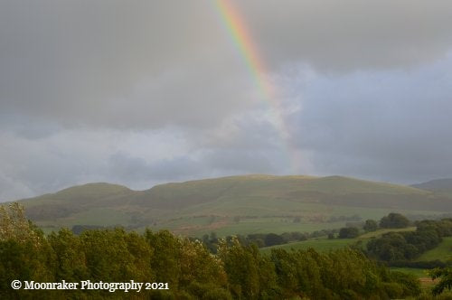View of a hill with a rainbow touching down