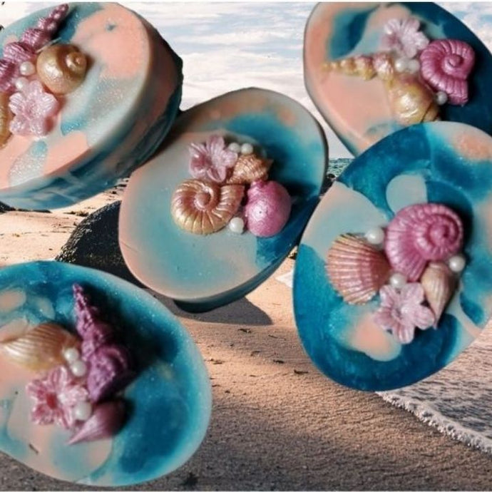 Blue and peach soap in swirling wave patterns with decorative shells on top made of soap.