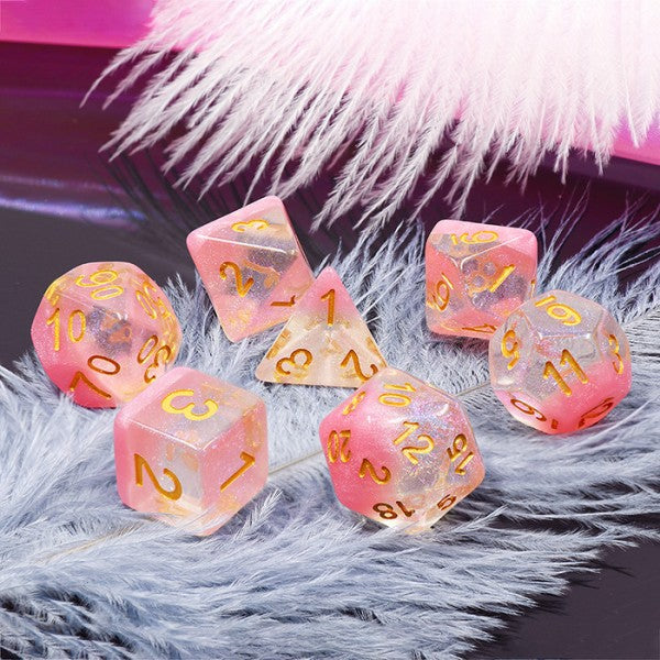 A tabletop dice set in translucent pink with gold numbers.
