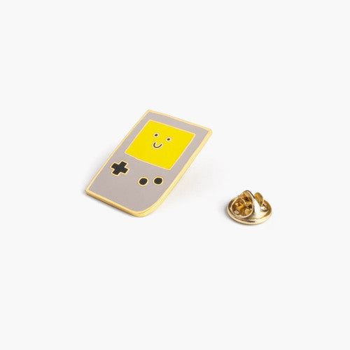 Enamel pin depicting an old-school Gameboy with a smiling screen.