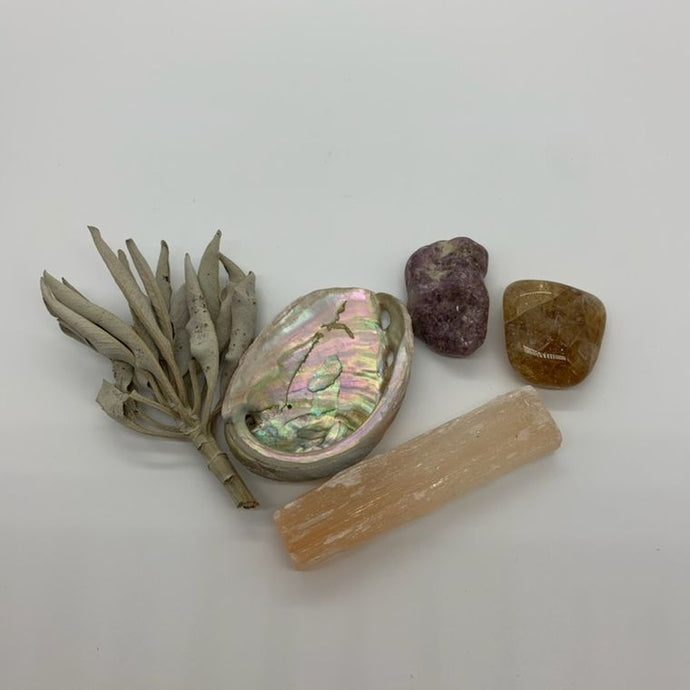Clockwise from left: sprig of sage, Shell with mother-of-pearl sheen, Lepidolite stone, Citrine stone, Orange Selenite stick.