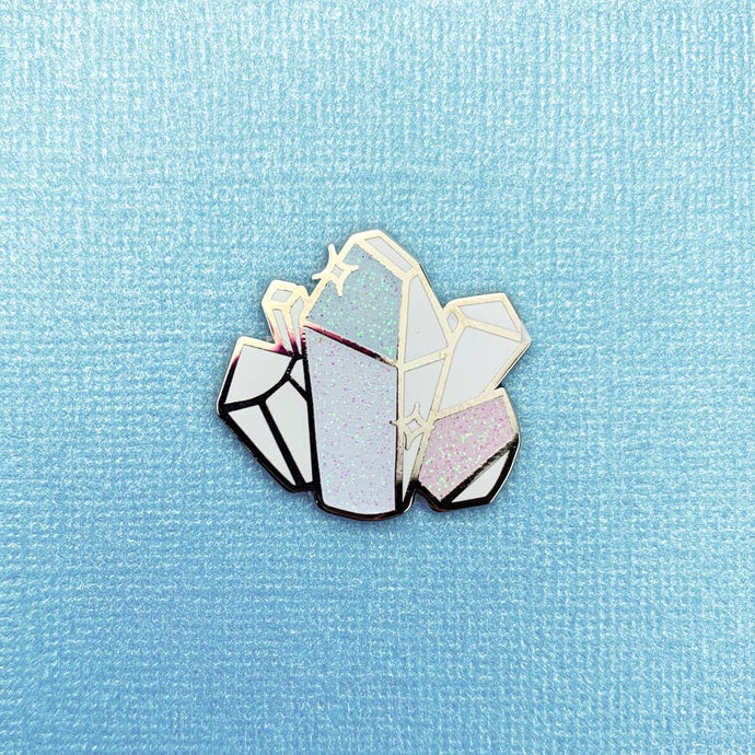 Enamel pin depicting several sparkling, stylized moonstone crystals.