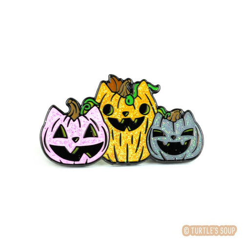 Enamel pin depicting three jack o' lanterns that look like cats.