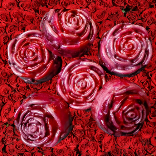 Red and pink rose-shaped soap on a background of red roses