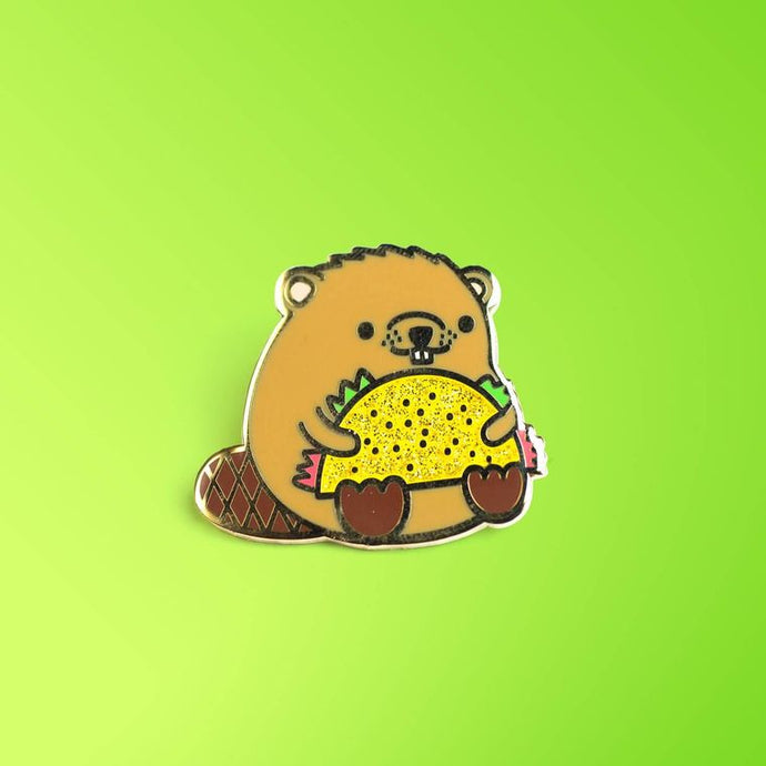 Enamel pin depicting a stylized beaver holding a taco in its arms.