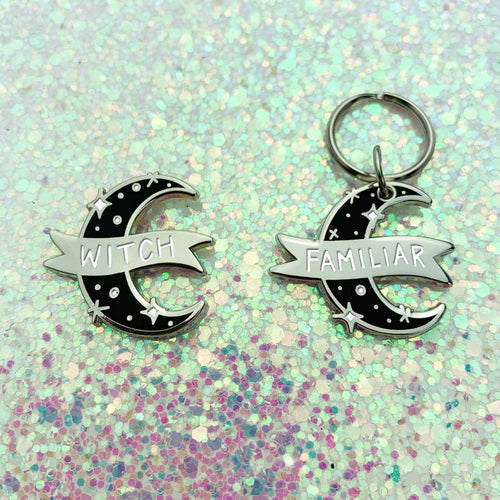 Enamel pin with a matching pet collar charm depicting a crescent moon in black with silver sparkles and a silver banner. The pin says 
